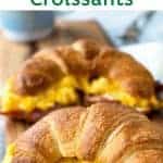 image with text. text reads "breakfast sandwiches bacon egg and cheese croissants". image is two croissants filled with scrambled egg on a wooden board.