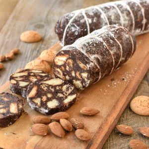 two chocolate salami on wooden board with three slices cut