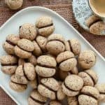 Pile of chocolate sandwiched hazelnut cookies on a white plate viewed from above