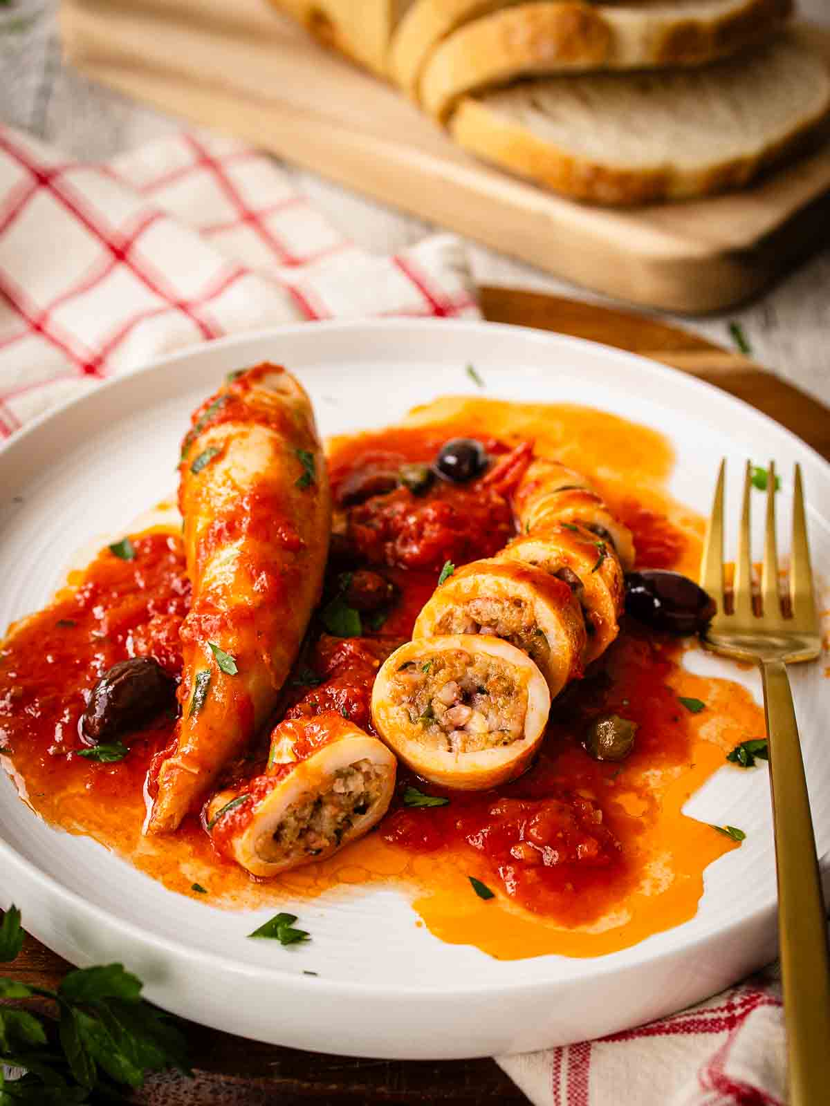 Stuffed Squid in tomato sauce on a plate, one whole and one sliced.