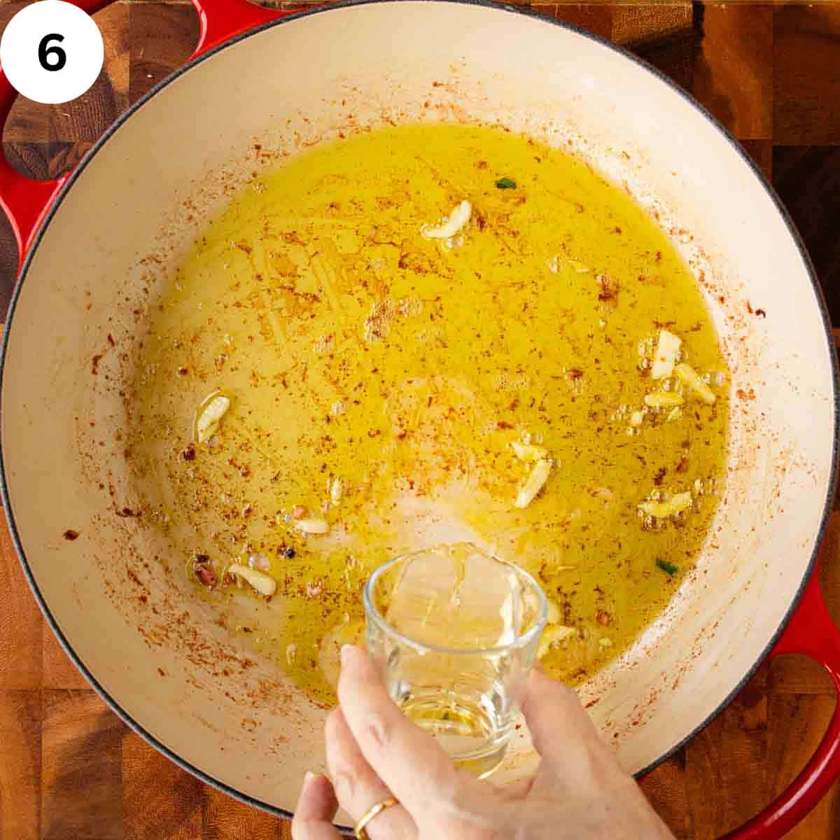 Pour clear liquid into a pan of oil and garlic.