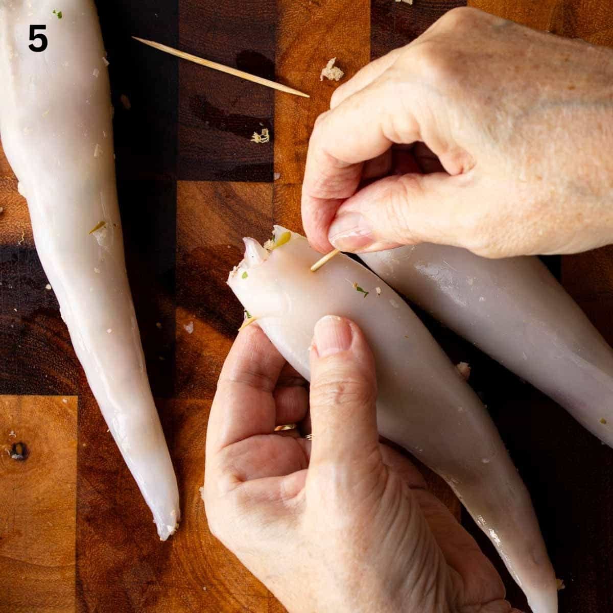 Pushing a toothpick through the open end of stuffed calamari tube.