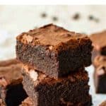 Three espresso brownies stacked with more brownies around.
