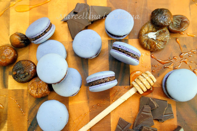 Finished Italian macarons on a table with chocolate and figs.