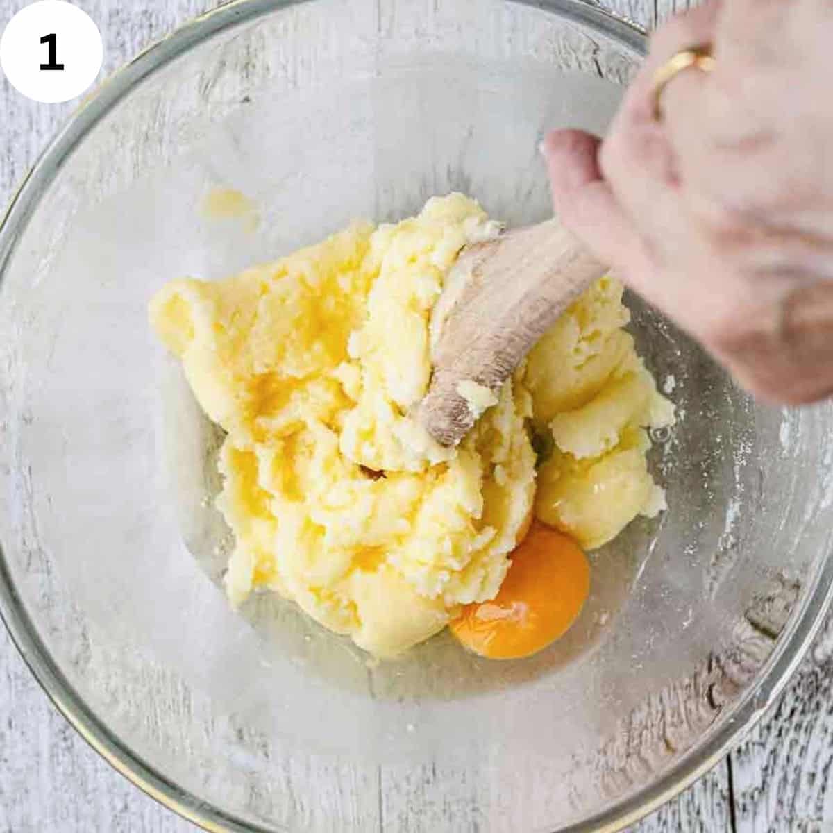 Butter, sugar and egg beaten with a wooden spoon in a glass bowl.
