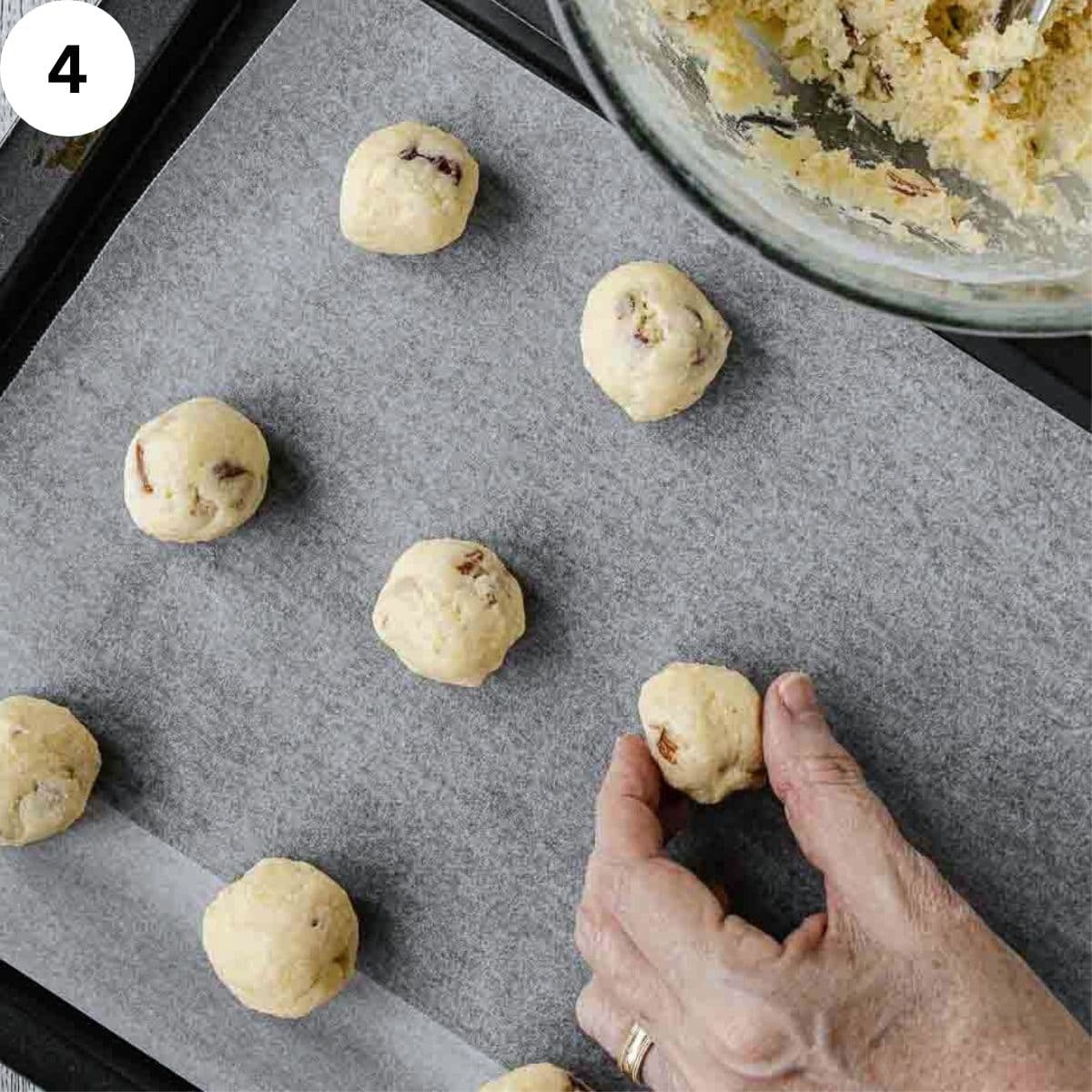 Cookie dough balls on a lined baking sheet.