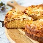 slice of cake with almond topping cut from whole cake viewed side on.