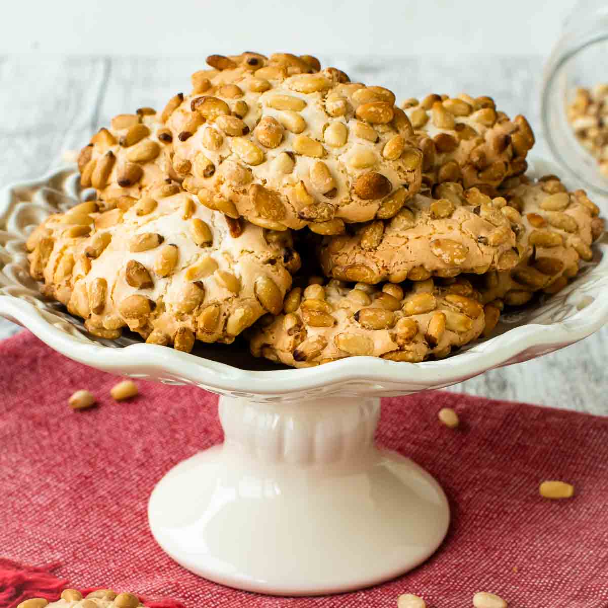 Pignoli Cookies on a white plate with a stand.