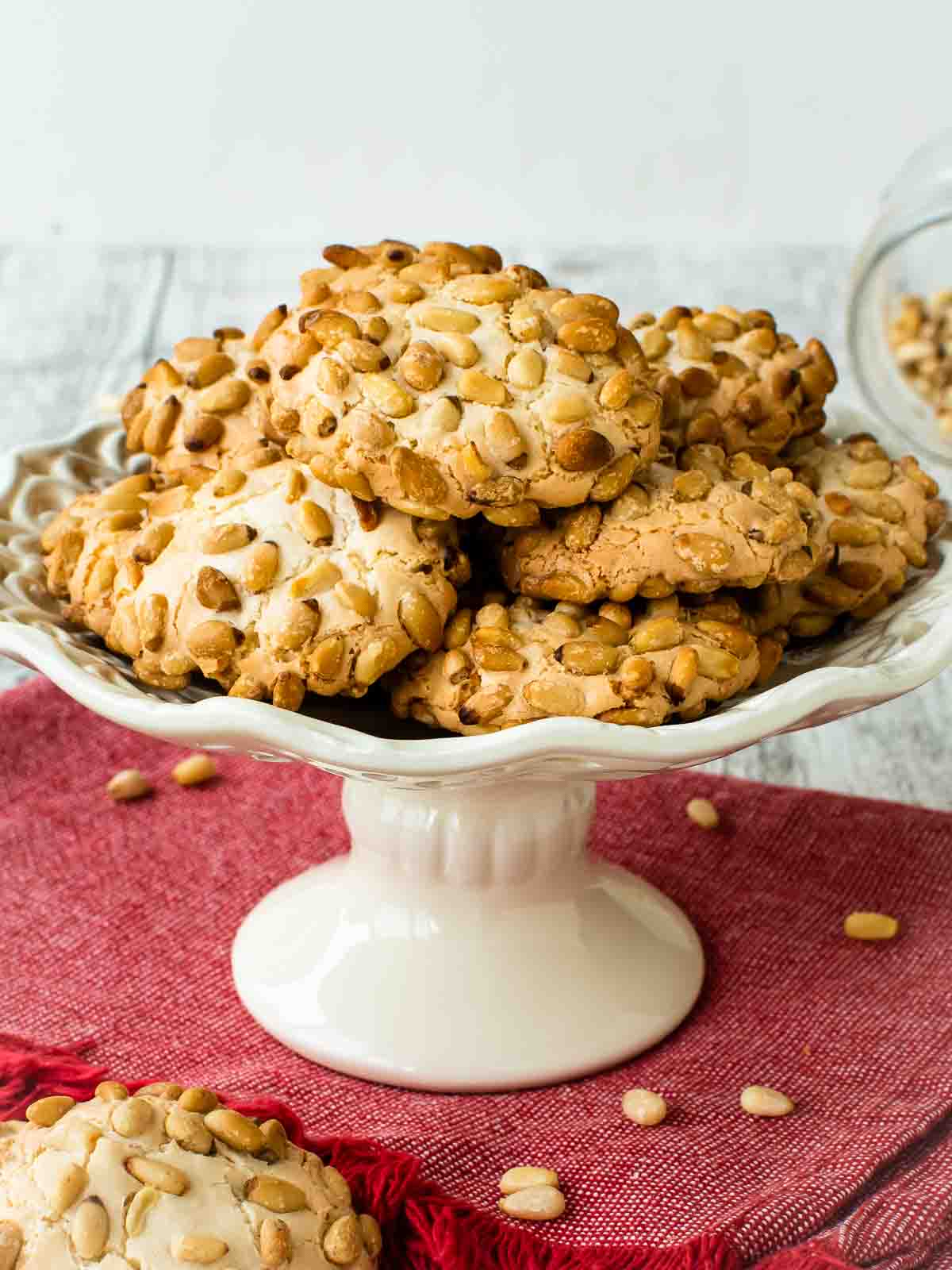 Pignoli Cookies on a white plate with a stand.