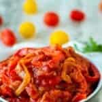 Stewed bell pepper and tomatoes in blue bowl.