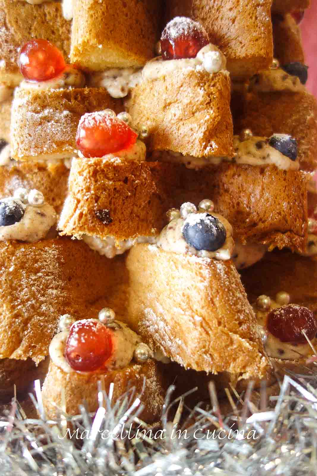 This Christmas Tree Cake delicious, spectacular and totally no bake! Do you need a great dessert for Christmas? Look no further. You will have this dessert made in less than 30 minutes. #christmasrecipe #italianrecipe #christmastreecake #pandorocake #nobakerecipe close up of cake layers show cream, blueberries and candied cherries.