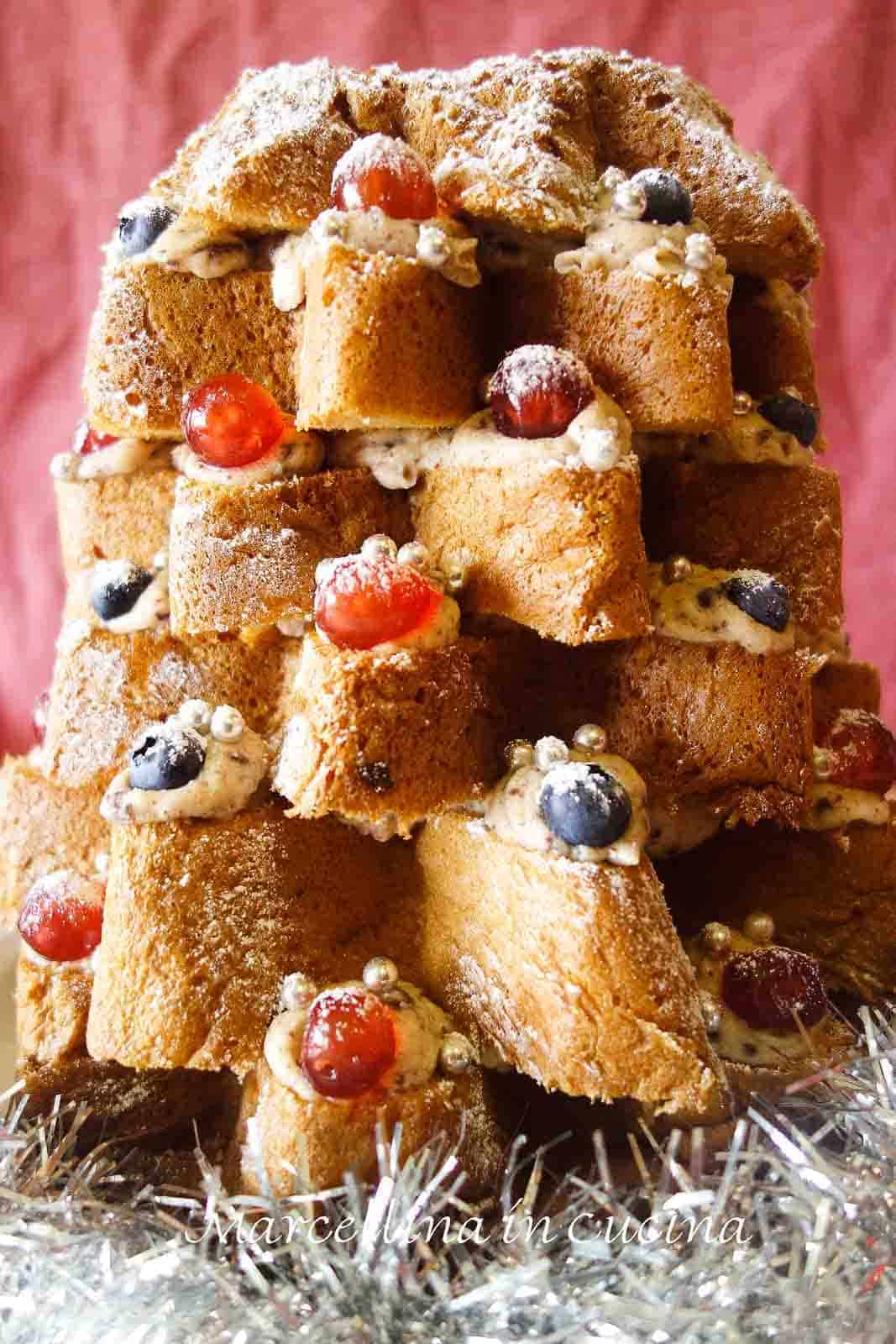 This Christmas Tree Cake delicious, spectacular and totally no bake! Do you need a great dessert for Christmas? Look no further. You will have this dessert made in less than 30 minutes. #christmasrecipe #italianrecipe #christmastreecake #pandorocake #nobakerecipe Pandoro Christmas tree cake with layers of cream filling, decorated with cherries and chocolate.