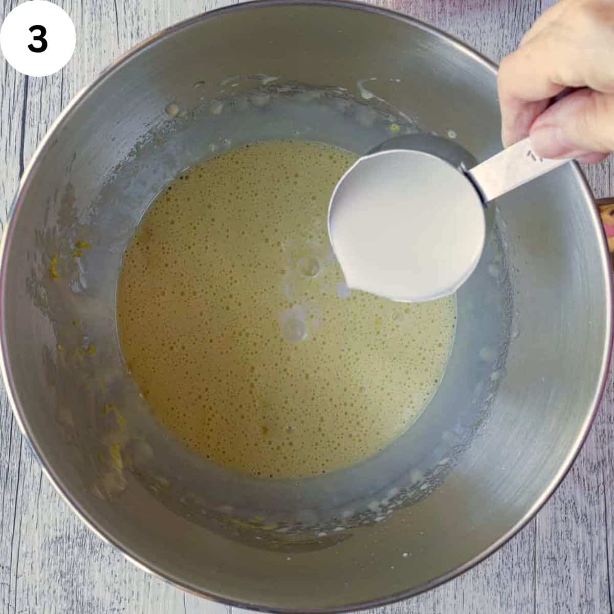 Adding milk to yellow frothy batter.