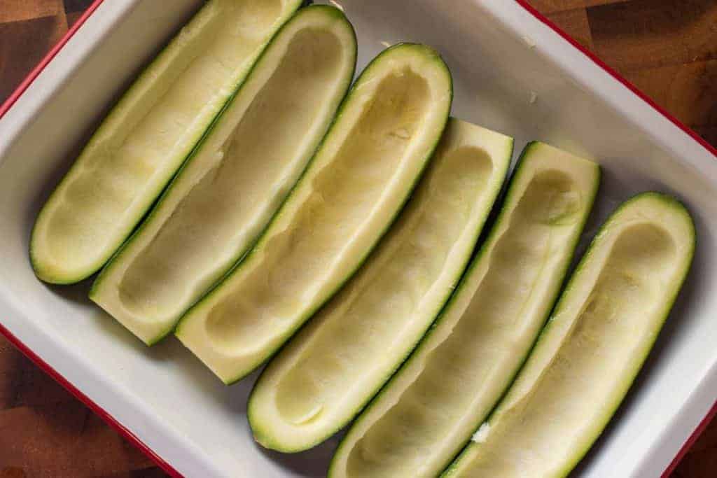 Six hollowed out green zucchini halves.