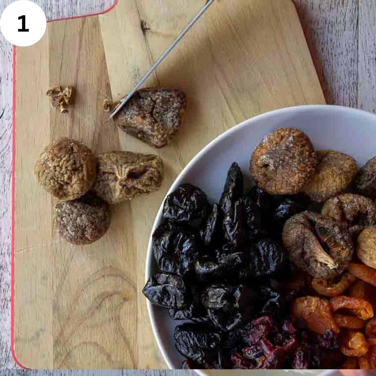 A variety of dried fruits and a bowl and dried figs on a wooden board.