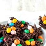 Chocolate nests with colored candy eggs on a white plate.
