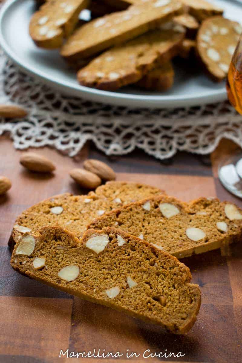 two Italian Piparelli - spicy cookies with glass of liqueur and a plate of cookies in the background