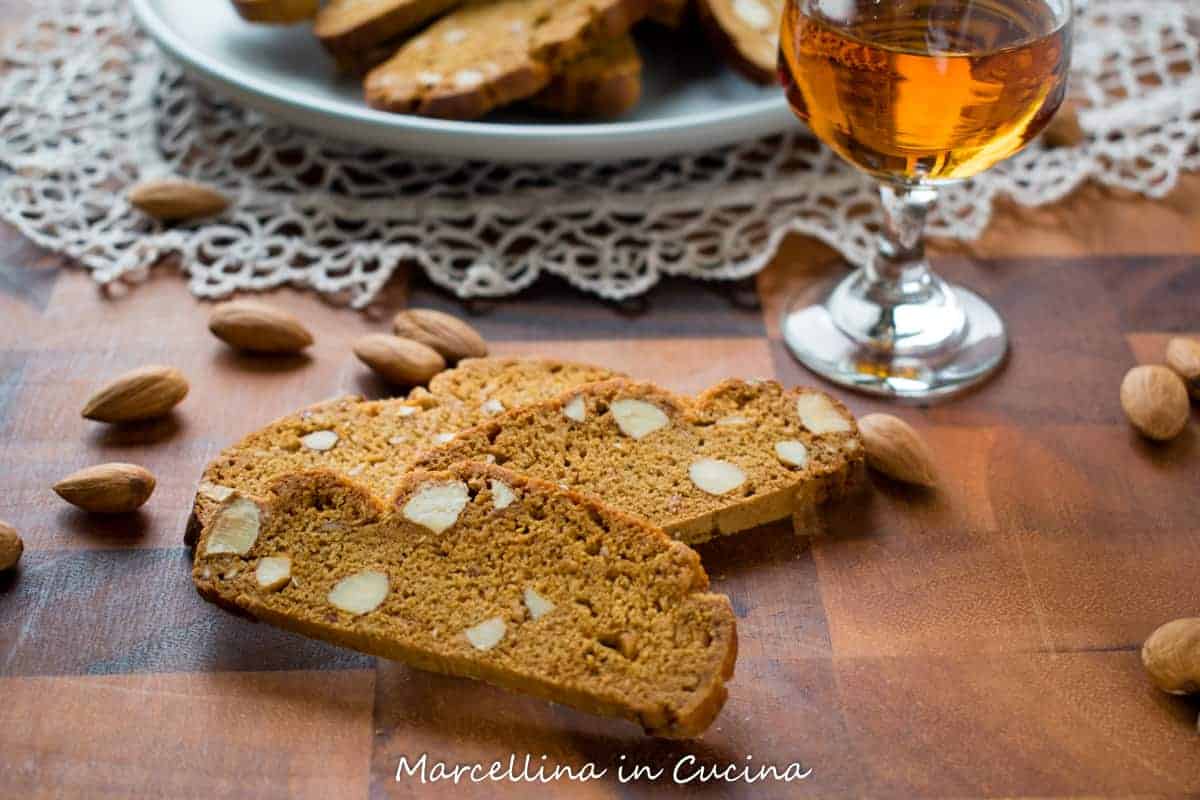 Italian Piparelli are traditional spicy biscotti perfect for dunking. #biscotti #italianrecipe #recipe #cookie #piparelle #sicilian Italian Piparelli, spicy biscotti on wooden table with glass of liqueur and plate of biscotti in the background
