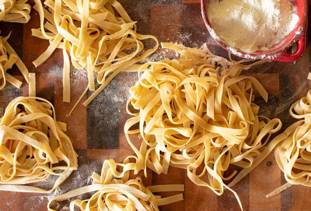 Fresh egg tagliatelle with small red dish of flour