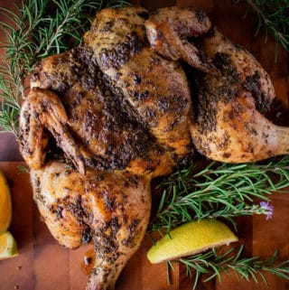 Roasted whole butterflied chicken on wooden board.