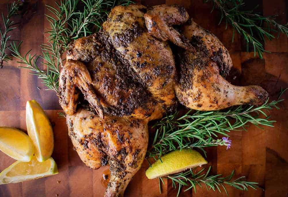 Roasted whole butterflied chicken on wooden board.
