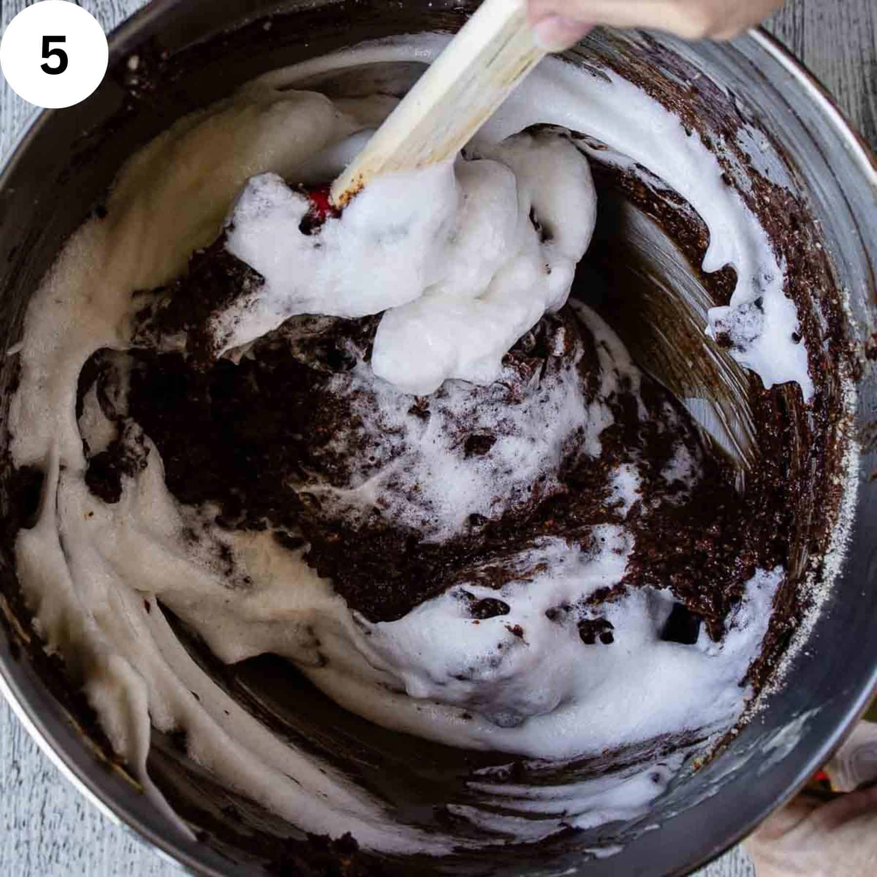 Beaten egg whites being folded into melted chocolate mixture.