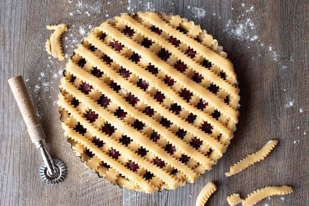 This Strawberry Crostata recipe | Easy Strawberry Tart is an easy Italian pastry filled with fruity jam #strawberrycrostata #crostatarecipe #strawberrytart #crostatadough Top of unbaked strawberry crostata recipe with pastry lattice work.