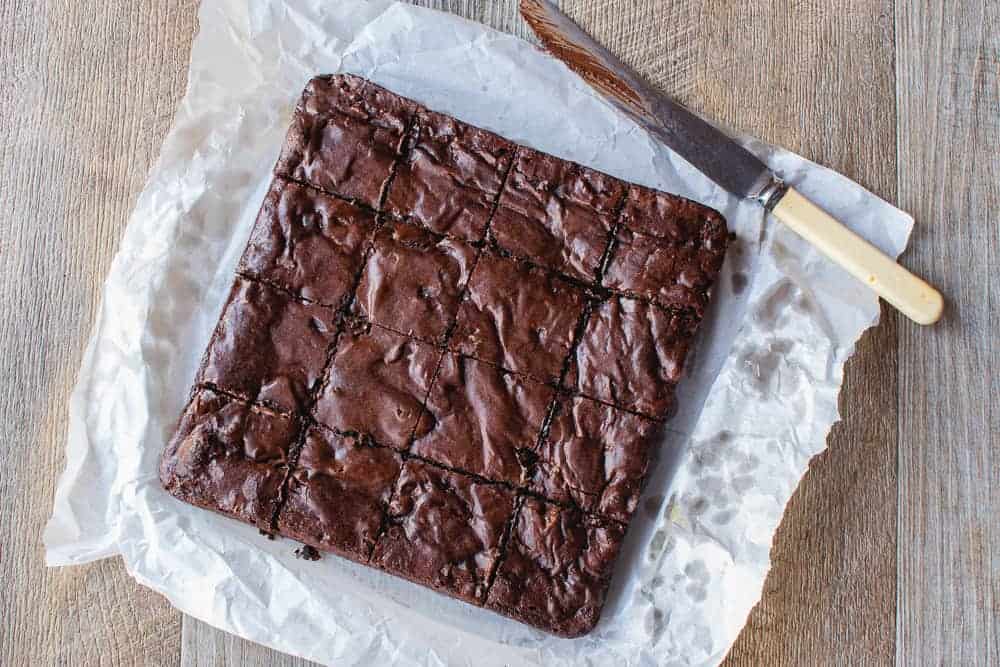 This Easy Brownies recipe with cocoa powder is rich and deliciously fudgy. You'll love this homemade, one-bowl recipe. #brownies #cocoabrownies #easybrownies #chocolatebrownies The brownies shown on baking paper from above, ready to be cut into squares