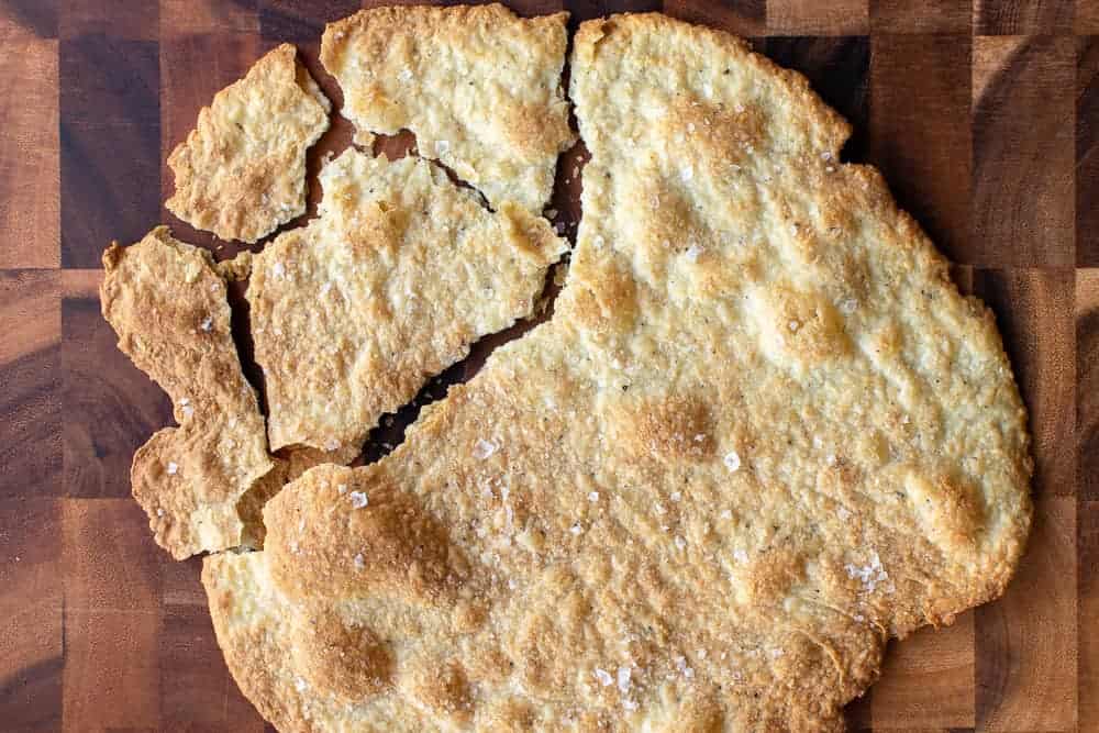 Homemade crackers are simply delicious, easy and so inexpensive to make. #homemadecrackers #crackers #cheese #artisan Large round cracker partly broken into serving pieces on a wooden table