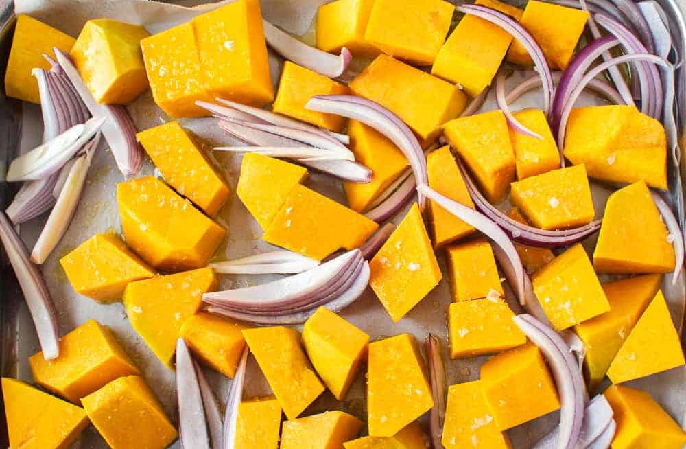 A delicious salad of Pumpkin and Spinach with feta and pepitas. #pumpkin #spinach #salad #feta pieces of orange pumpkin and slices of red onion.