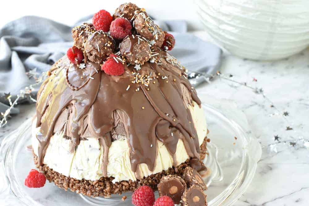 Christmas Ice cream pudding is made with store bought ice cream so it's perfect for that last minute impressive Christmas dessert . #christmaspudding #icecreampudding #christmasicecreamdessert #icecreamdessert #pudding #dessert christmas ice cream pudding with chocolate drip decorated with chocolates and raspberries