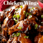 Honey baked chicken wings on blue plate with bowl of sauce with white plates, forks and red paper serviettes