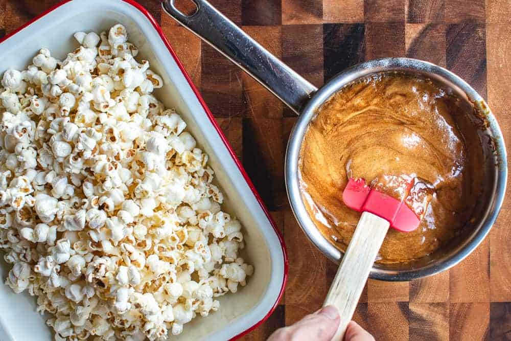 Caramel popcorn with nuts is a delicious and easy snack which everyone loves! #caramelcorn #bestcaramelcorn #caramelcornwithnuts #caramelpopcorn A pot of caramel and a tray of popcorn shown from overhead.