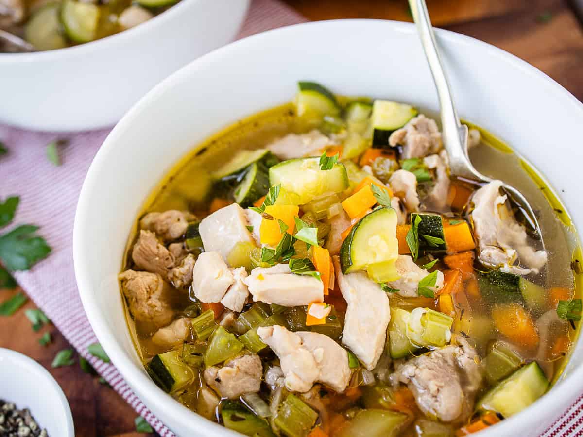Close up of a bowl of soup of chicken and vegetables.
