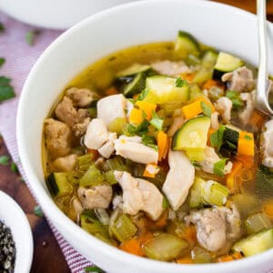 A bowl of chicken vegetable soup with bread.