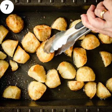 Partially roasted potatoes being turned with tongs.