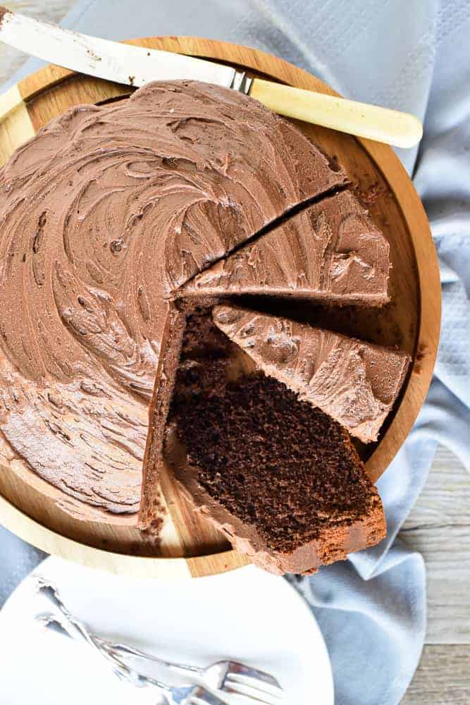 This homemade Chocolate Cake recipe is just as easy as a box cake but much more delicious! Topped with simple chocolate frosting, everyone will be asking for seconds! #homemade #chocolatecake #homemadecake #homemaderecipe #cakerecipe Chocolate cake with frosting and three slices cut viewed from above.