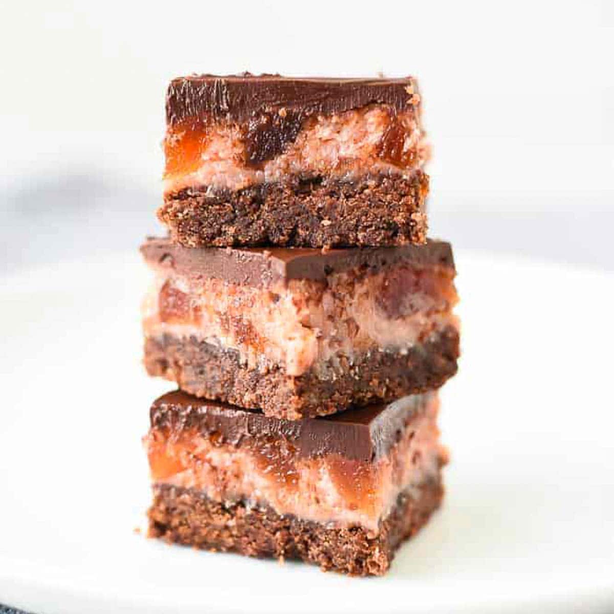 Three Cherry Ripe Bars stacked one on top of the other on a white plate viewed front on.