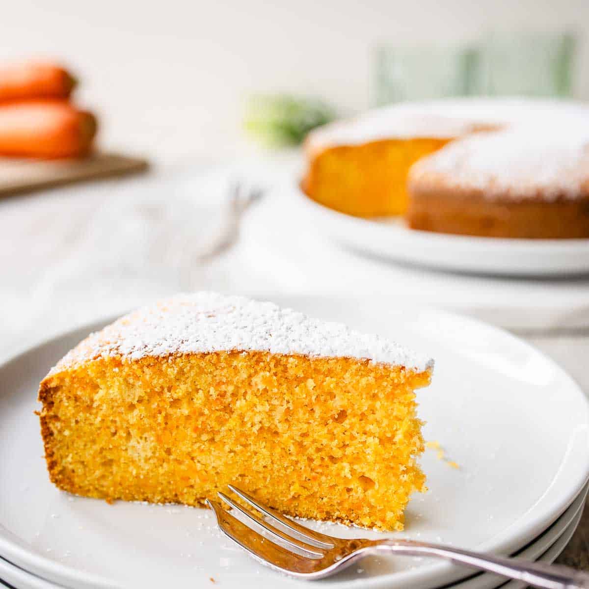 Wedge of Italian carrot cake on three stacked white plates.