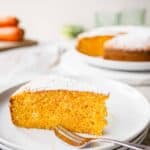 Wedge of Italian carrot cake on three stacked white plates.
