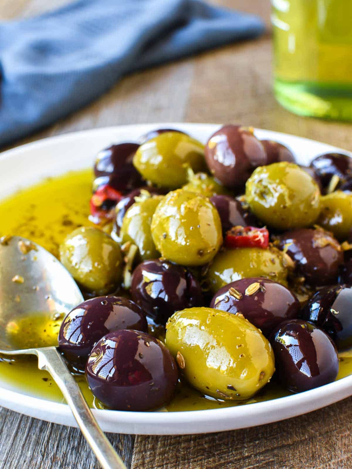 Marinated olives on a round plate with spoon.