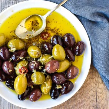 Olives with flavorings and oil on a plate viewed from above