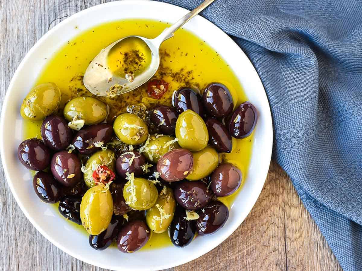 Olives with flavorings and oil on a plate viewed from above