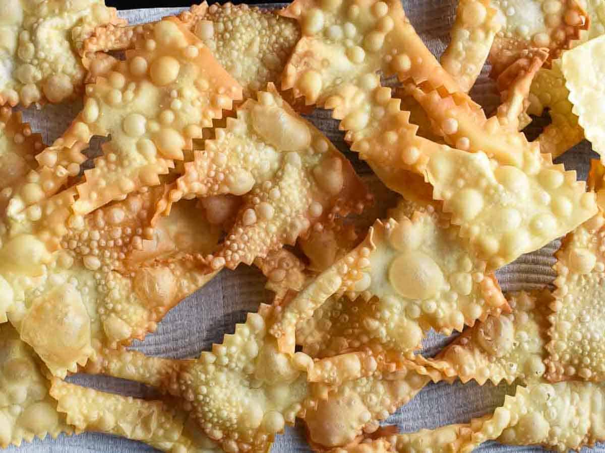Crostoli are a crispy fried Italian pastry that is popular during Carnevale and many other celebrations. Try stopping at just one - impossible! #crostoli #angelwings #Italianfritters #easter #christmasrecipes #lent #Italiancookie #italianrecipes Fried and bubbled pastry strips viewed from above