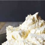 Italian meringue buttercream in black bowl viewed from the side. This is a pin image with text