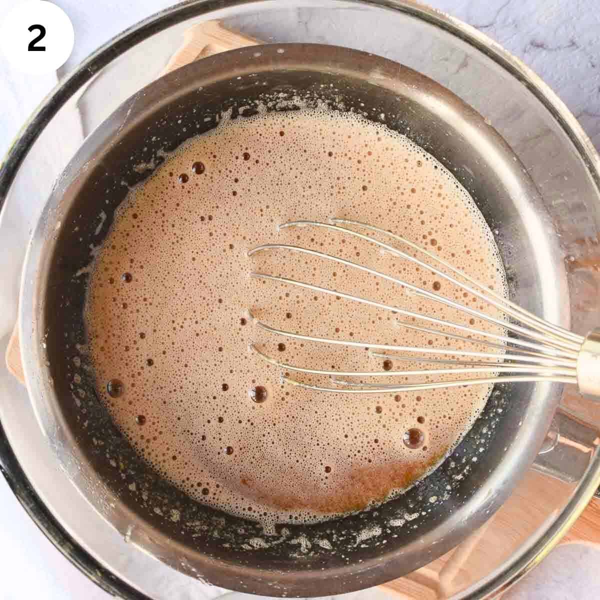Whisking brown creamy liquid in a glass bowl.