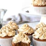 Coffee Cupcakes on black wire rack with a bite taken out of one cupcake.
