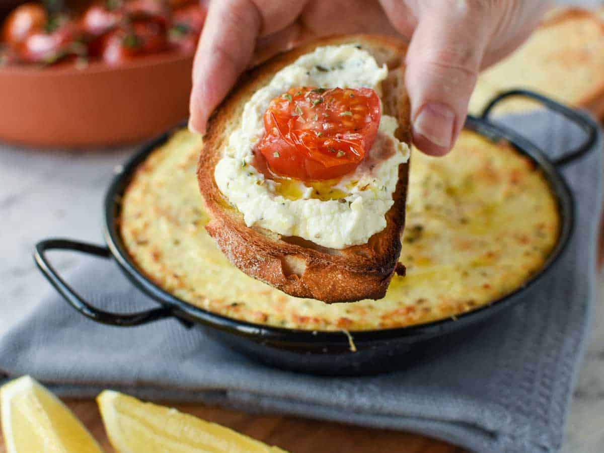 30 minutes. Serves 8. This Creamy Baked Ricotta Dip is full of lemon and garlic flavours. Serve with Roasted Tomatoes and crusty bread for a delicious, savory appetizer. slice of toasted bread spread with white creamy dip and topped with half a slice of roasted cherry tomato.