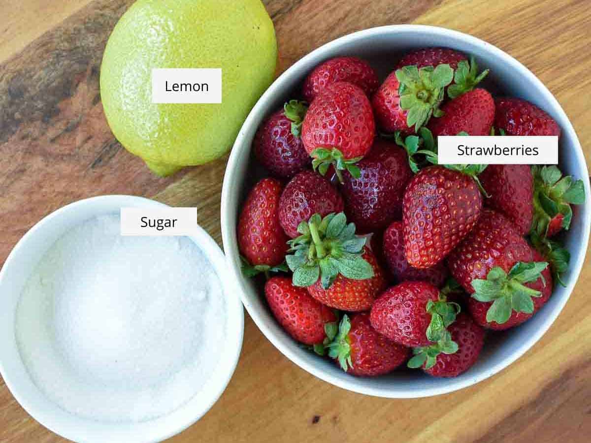 A homemade Strawberry sauce recipe using just 3 ingredients that is perfect for all desserts. You'll love using this strawberry topping for ice cream, pancakes or cheesecakes. #strawberries #dessert #sauce #strawberrysauce #strawberry #homemade a lemon, a bowl of strawberries and a bowl of white sugar