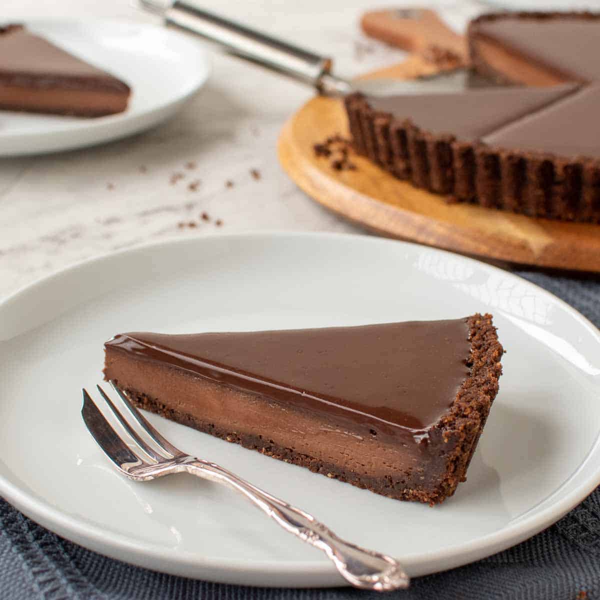 slice of chocolate tart with whole tart in the background